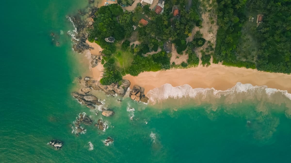 Aerial view of turquoise water meeting palm-fringed sand near Bentota, Sri Lanka