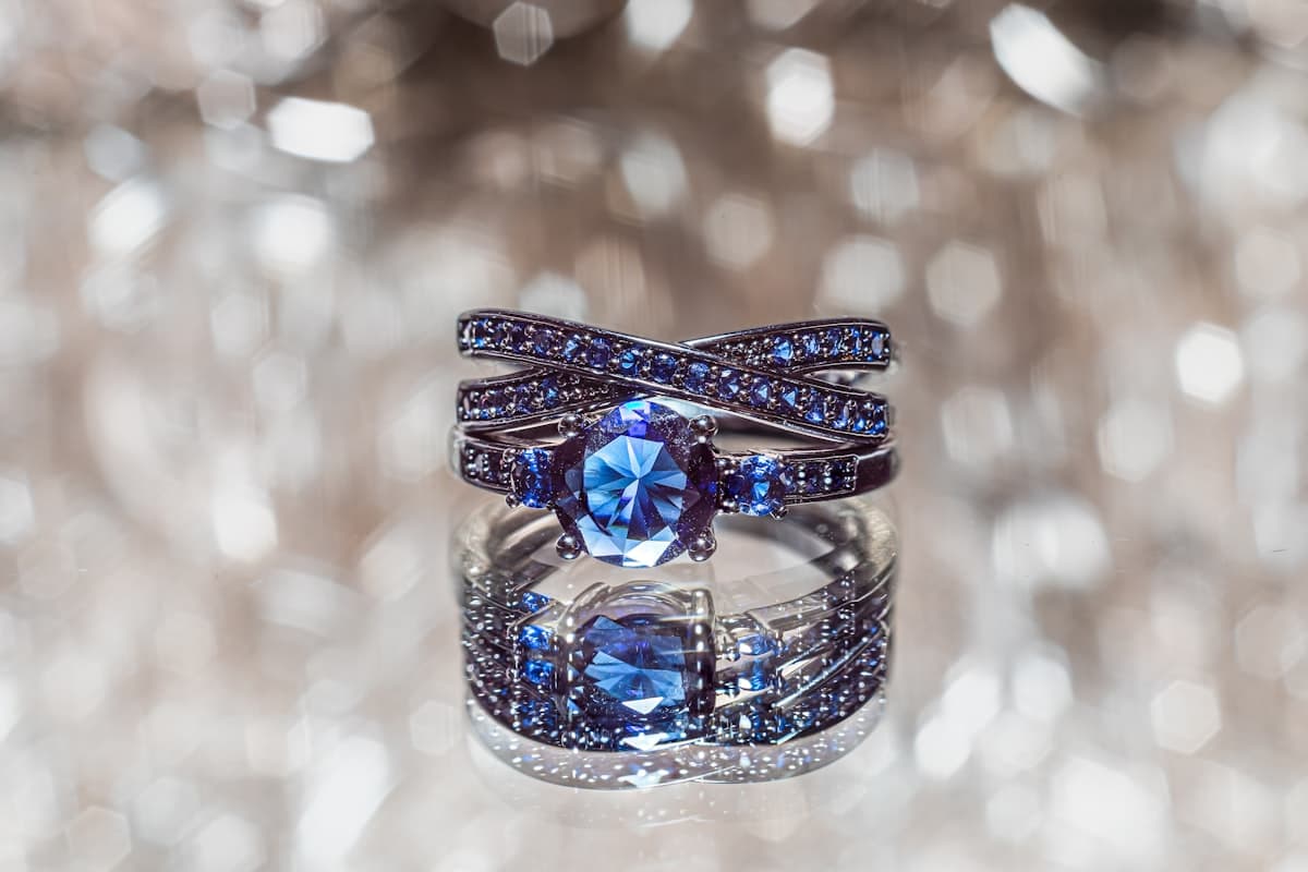 A Ceylon blue sapphire set in a ring, photographed against a soft bokeh of cut stones