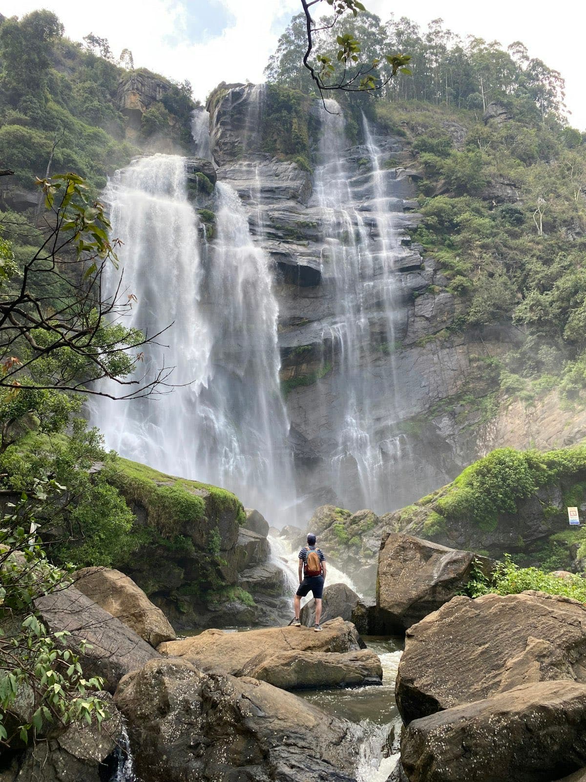 Ravana Falls near Ella, Sri Lanka — a traveller dwarfed by the jungle waterfall