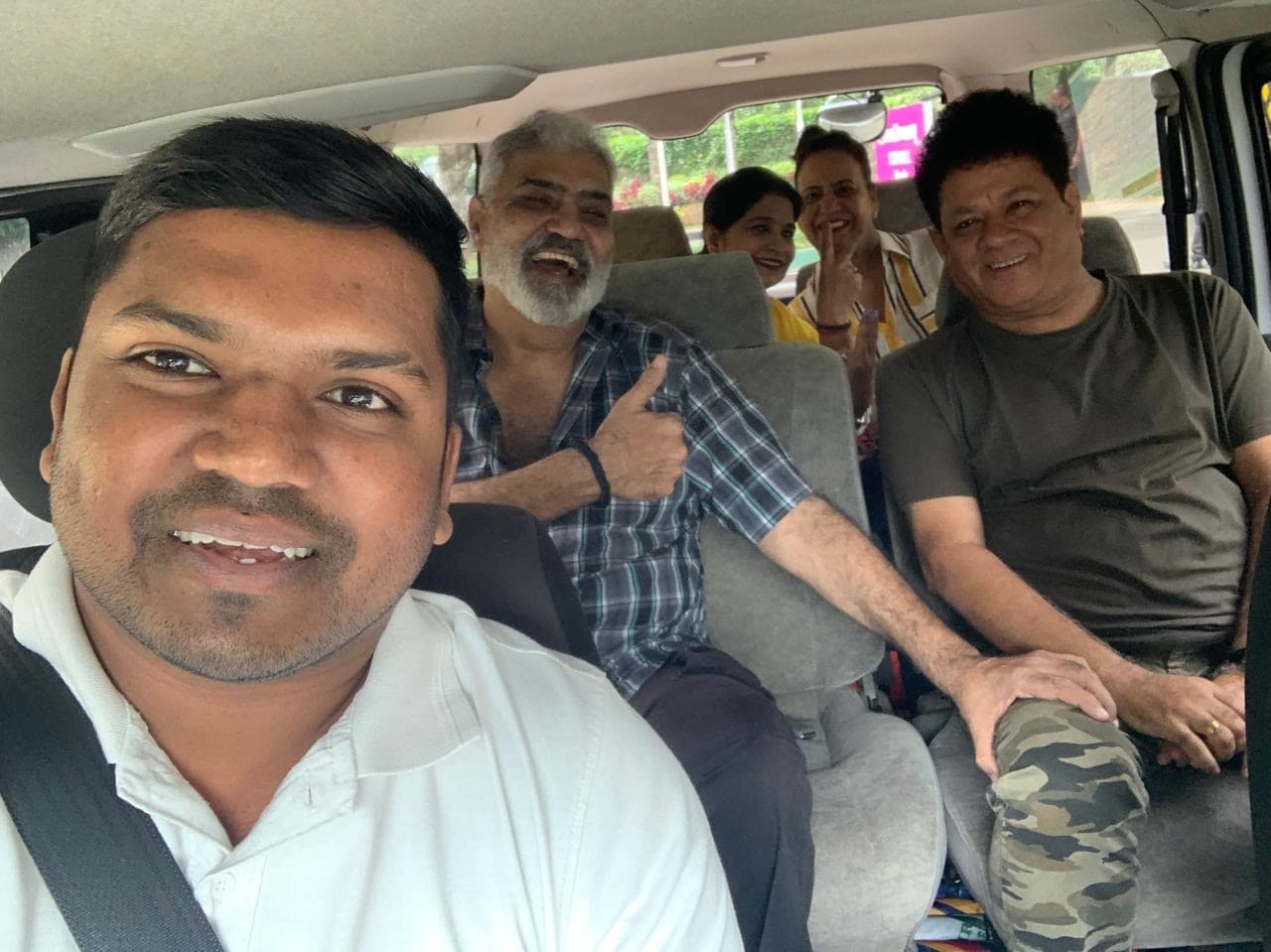 Chauffeur-guide at the wheel of a private tour van with four happy guests seated behind him